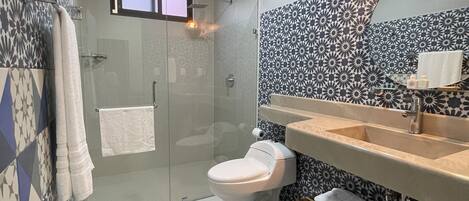 Une salle de bain moderne avec une douche à parois de verre, des toilettes blanches et un lavabo avec un miroir.