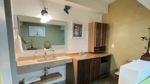 Une cuisine de taille réduite, dotée d’un plan de travail en bois, d’un évier et d’un miroir.