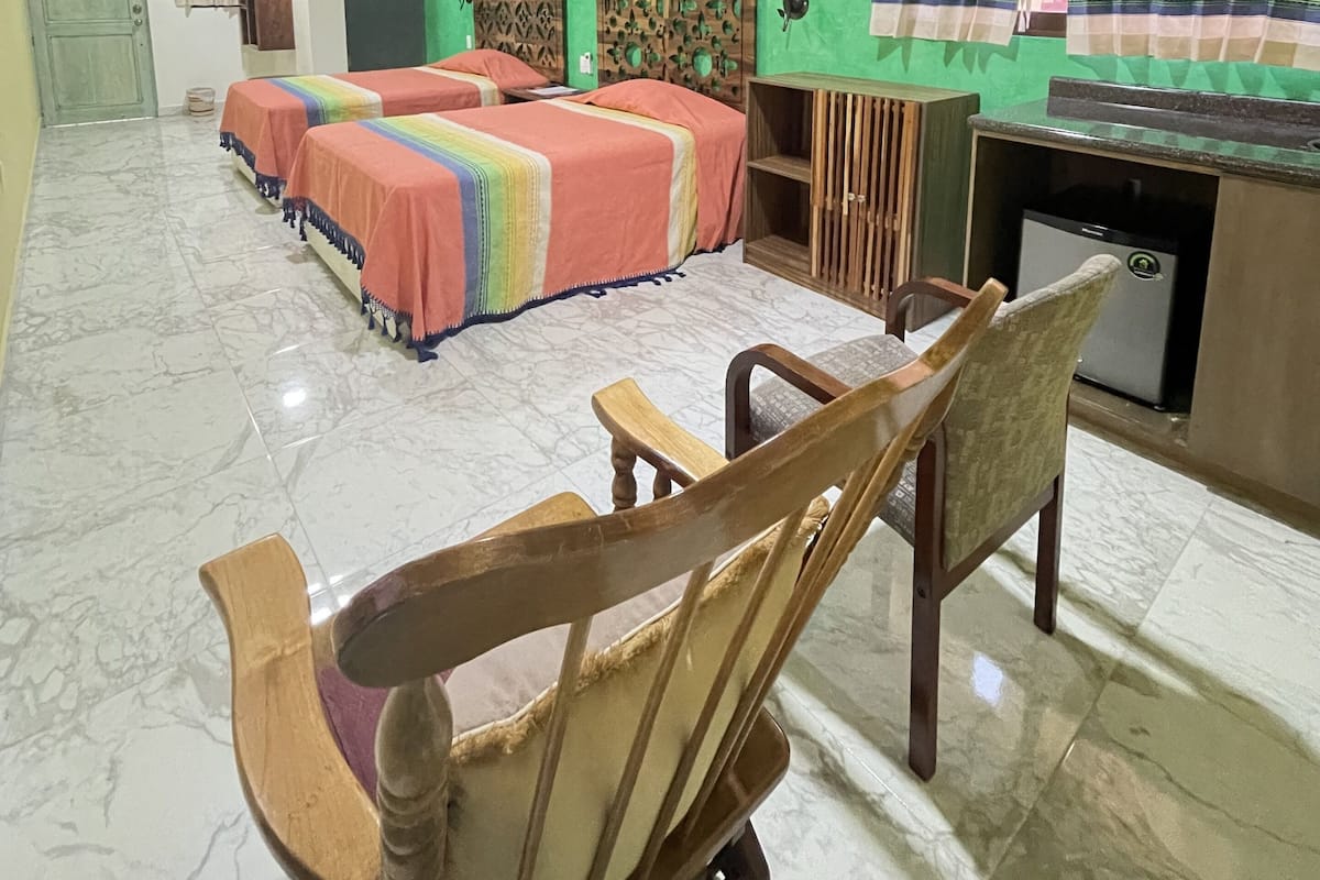 A hotel room with a bed, a desk, a chair, and a small refrigerator.