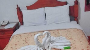 A hotel room with a bed, a nightstand, and a red wall. - HOSTAL MONARCA (Cusco)