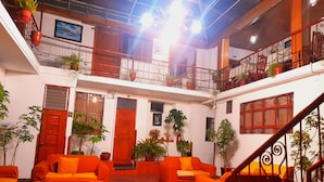 A spacious indoor area with multiple seating arrangements and potted plants. - HOSTAL MONARCA (Cusco)