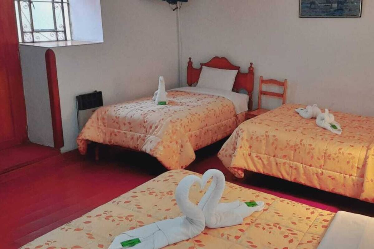 A hotel room with two beds, a red staircase, a window, and a wall-mounted painting.