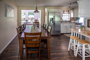 A kitchen with a dining table, chairs, a refrigerator, and a bar area. - Countryside Mountain house with awesome views (Clyde)