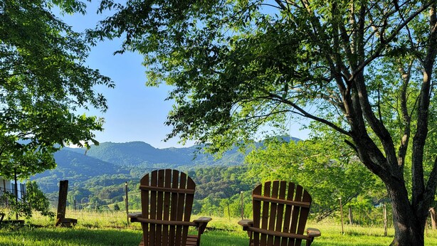 Deux fauteuils Adirondack sont placés face à un paysage magnifique, avec des montagnes et un lac en toile de fond.