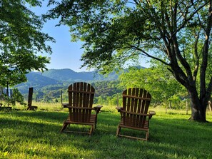 Deux fauteuils Adirondack sont placés face à un paysage magnifique, avec des montagnes et un lac en toile de fond.