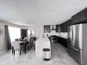 Une cuisine moderne avec des meubles de couleur sombre, des appareils électroménagers en acier inoxydable et un îlot central.