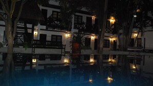 A nighttime view of a hotel with a swimming pool, reflecting the building's architecture and surrounding trees. - Vientiane Garden Villa Hotel (Vientiane)