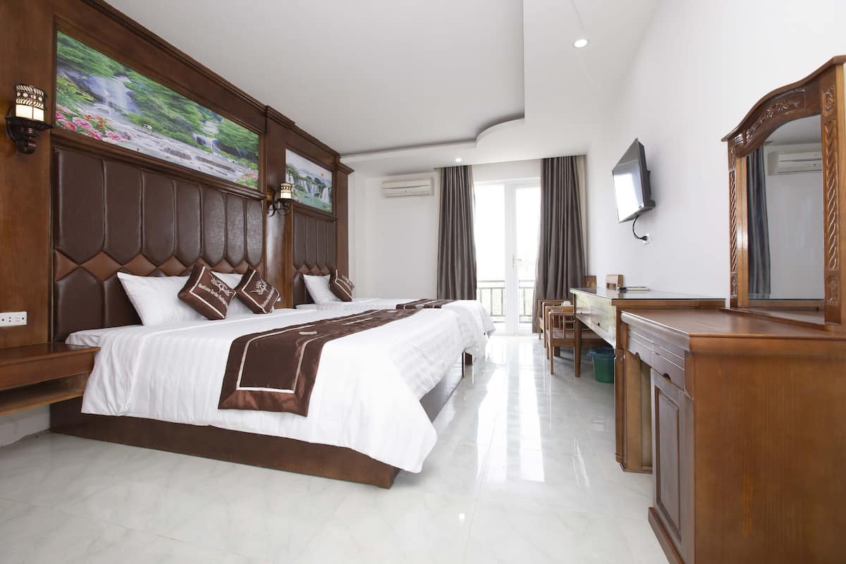 A hotel room with a large bed, a desk, a mirror, and a television.