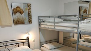 Une chambre avec un lit superposé, dotée de linge de lit blanc et d’une lampe de chevet.