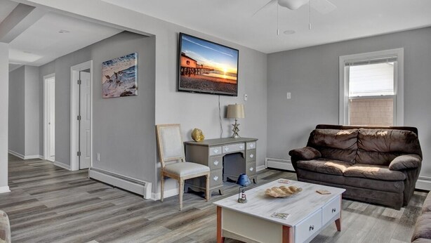 A living room with a fireplace, a sofa, a coffee table, and a TV mounted on the wall. - 🏖 Beautiful Bay View Condo “Close To Beach” 🏖 (Ventnor City)