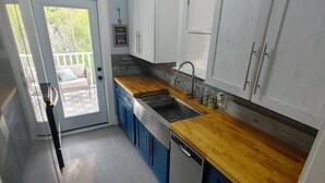 Una cocina compacta con armarios blancos, encimera de madera y lavavajillas integrado.