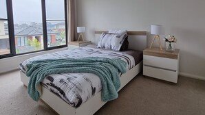 Een moderne slaapkamer met een groot bed, nachtkastjes en een uitzicht door het raam.