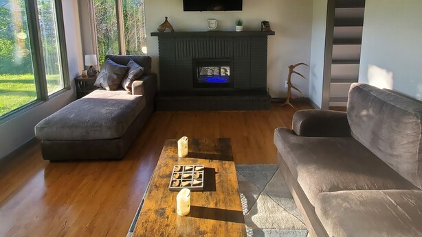 Una sala de estar moderna con chimenea, un sofá, una mesa de centro y un televisor montado en la pared.