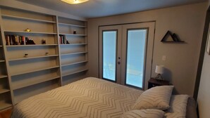 Un dormitorio con cama, estantería empotrada y lámpara en el techo.