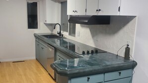 Cocina compacta con una isla central, un grifo negro y armarios blancos.