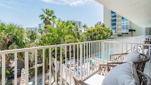 Ein Balkon mit Korbmöbeln, einem Pool und Palmen.