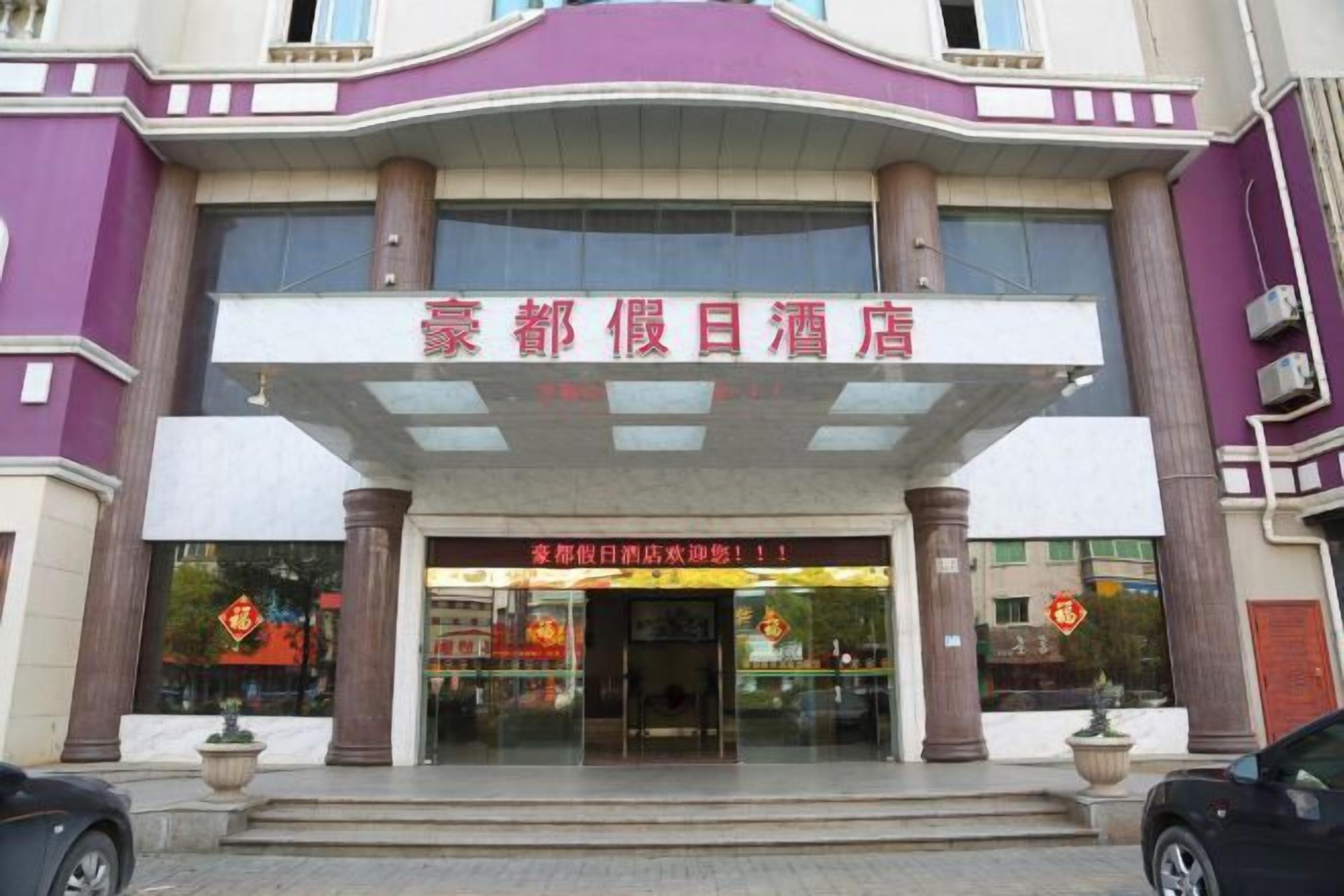A hotel entrance with a prominent sign, large windows, and a symmetrical facade.