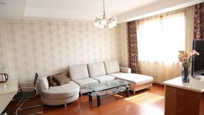 A living room with a sofa, a glass coffee table, a TV, and a vase with flowers. - Haining Haodu Holiday Inn (Haining)