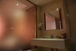 Un bagno con cabina doccia in vetro, un lavabo con specchio sopra e un portasciugamani.