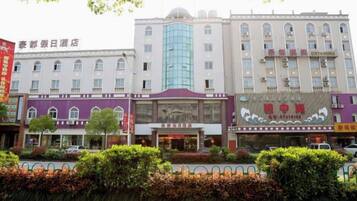 A hotel with a central entrance, multiple floors, and a large glass facade.