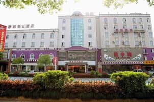 A hotel with a central entrance, multiple floors, and a large glass facade.