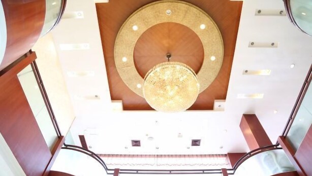 A modern interior with a large circular ceiling design, a chandelier, and a staircase. - Haining Haodu Holiday Inn (Haining)