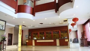 A hotel lobby with a reception desk, a staircase, and a decorative statue. - Haining Haodu Holiday Inn (Haining)