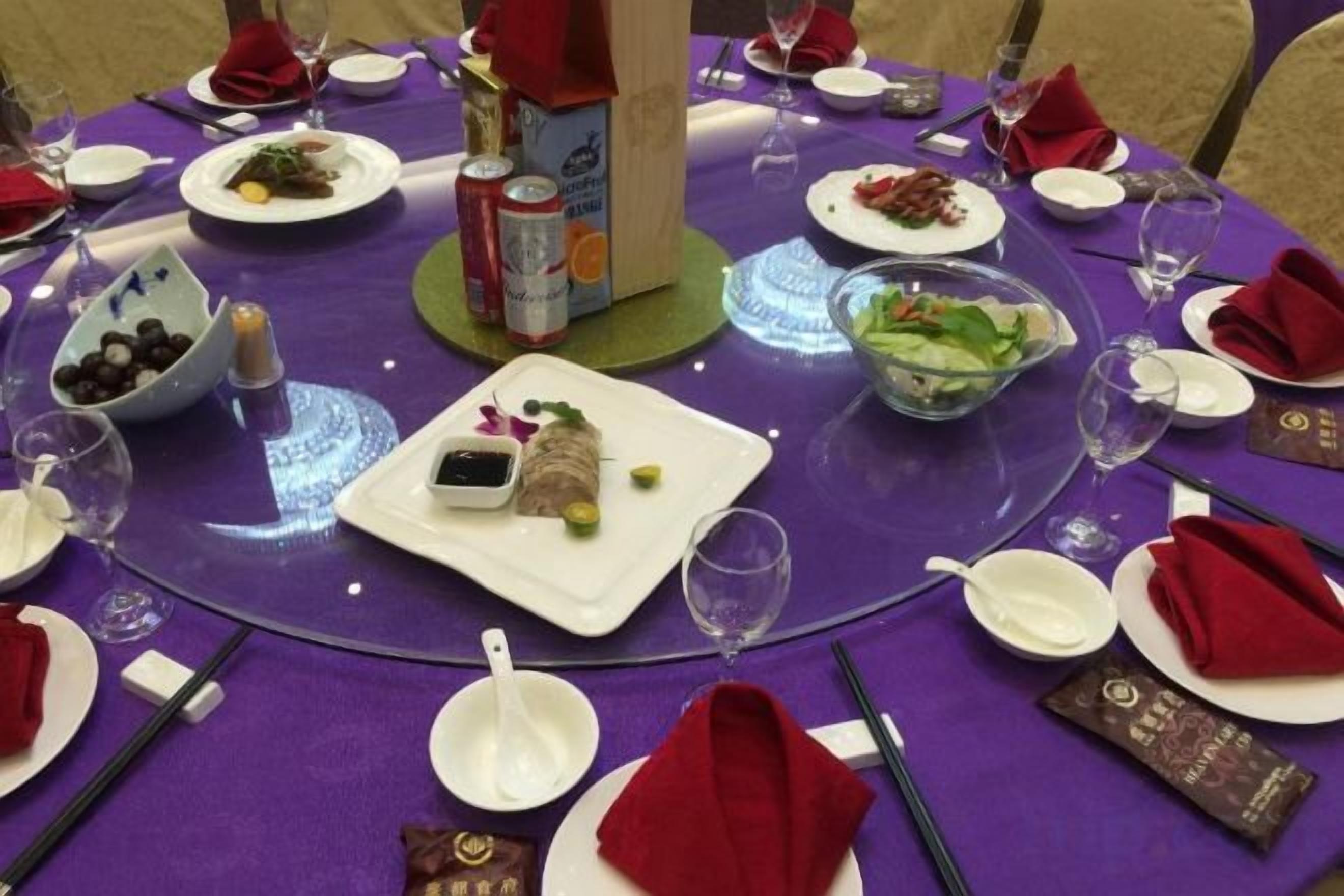 A round table set with plates, bowls, and glasses, indicating a dining arrangement.