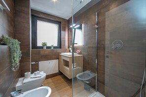 Enjoy a refreshing shower in the spacious bathroom with a clear enclosure and separate toilet area.