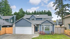 Ein zweistöckiges Haus mit Garage, Vorgarten und Holzlattenzaun.