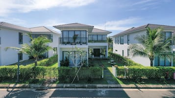 Un complejo residencial moderno con casas de dos pisos, césped cuidado y palmeras.