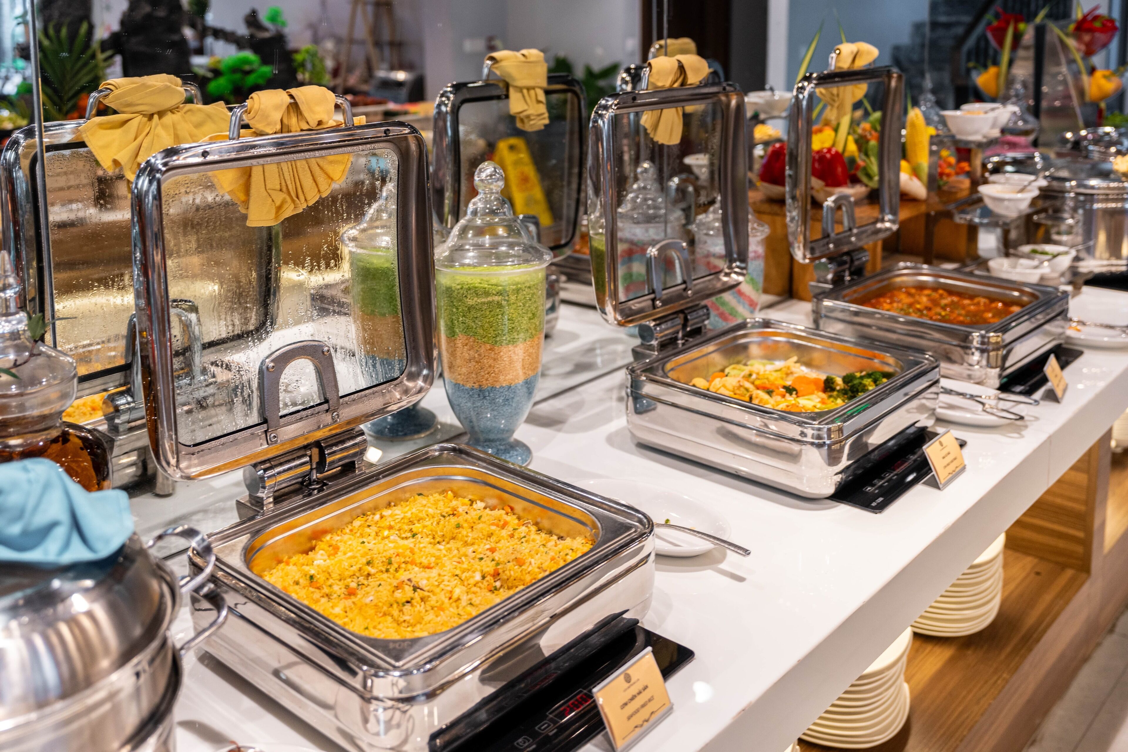 A buffet with various food items in glass containers, some with labels and a digital scale.