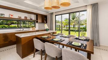 Une cuisine moderne dotée d’un îlot central, d’une table à manger avec des chaises et de grandes fenêtres offrant une vue sur l’extérieur.