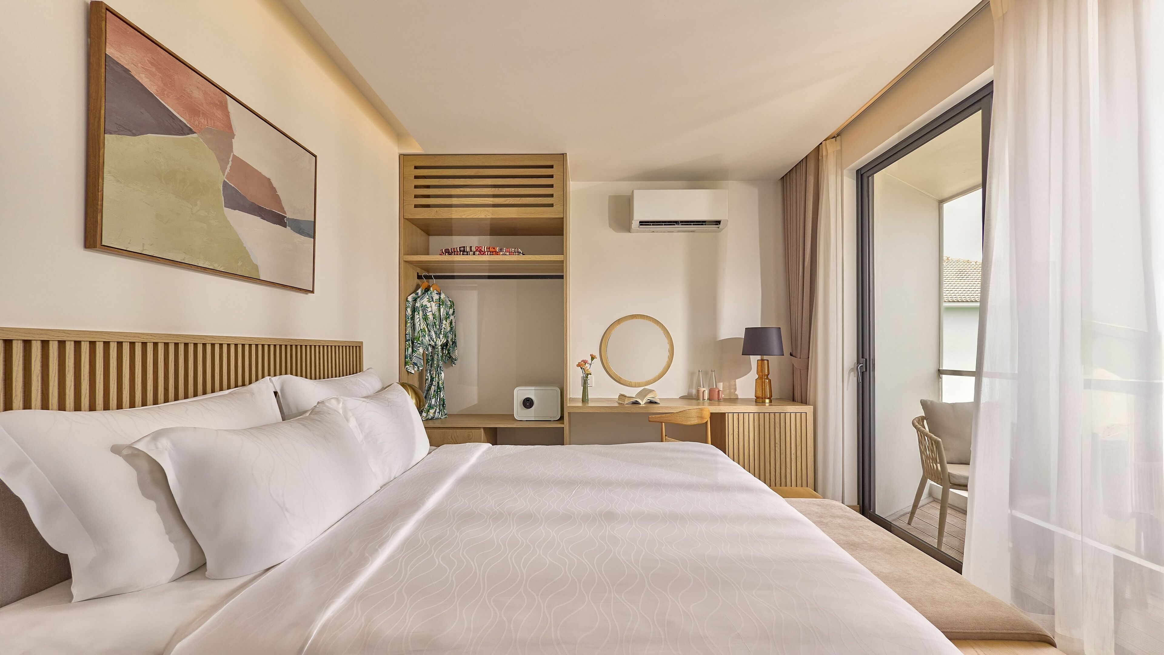 Et hotelværelse med en stor seng, et skrivebord med lampe, et spejl og et garderobeskab.