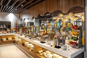 A buffet area with various food stations, including a salad bar, a hot dish station, and a fruit display.