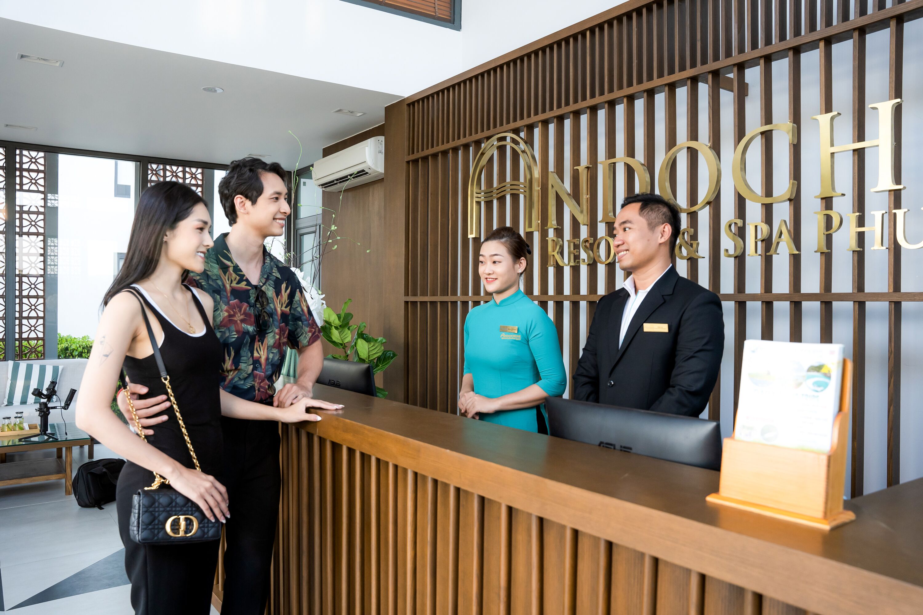 A reception desk with a wooden panel design and a sign that reads "ANDOCH RESORT & SPA PHU".