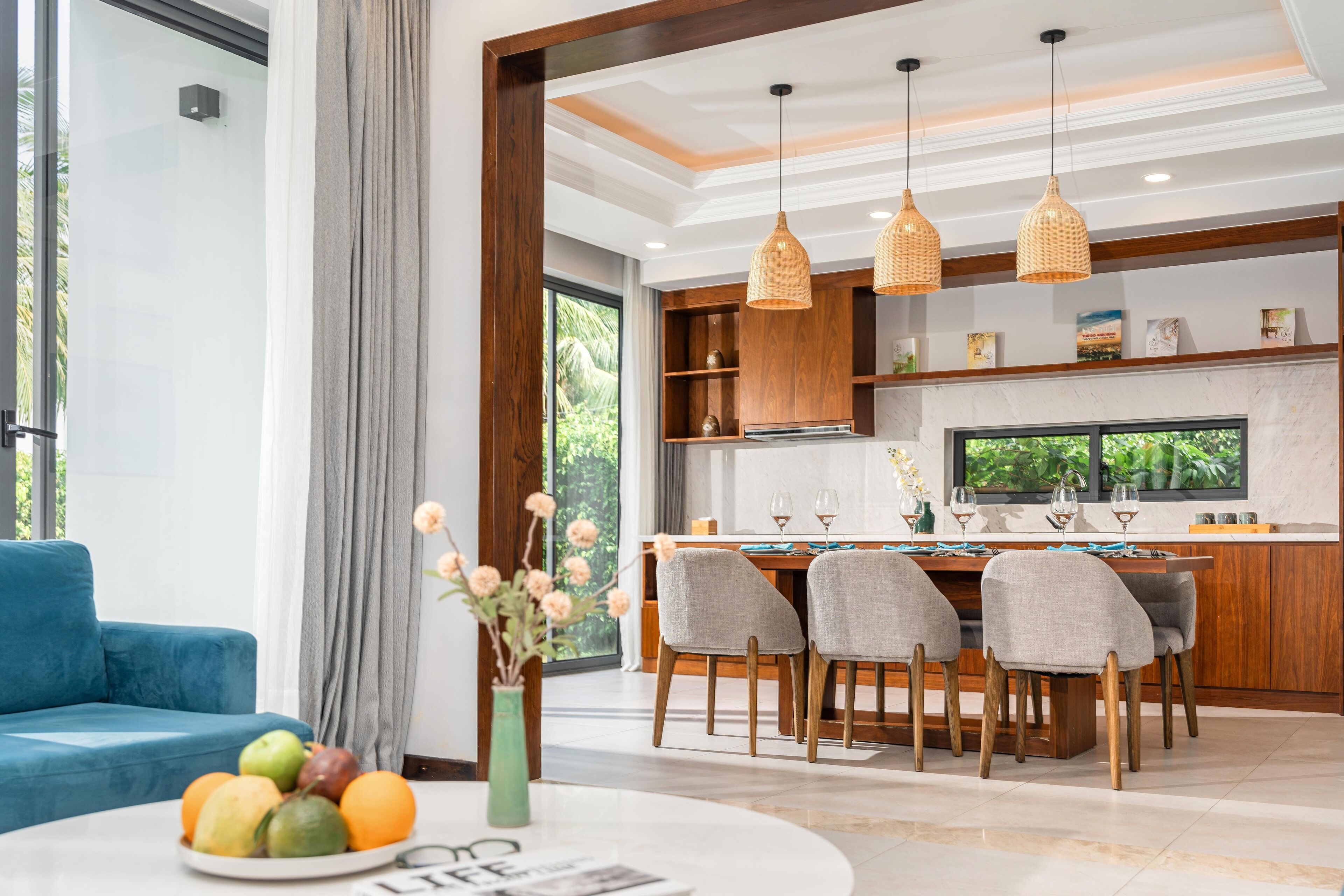 Una cocina moderna con armarios de madera, una mesa de comedor con sillas e iluminación colgante.
