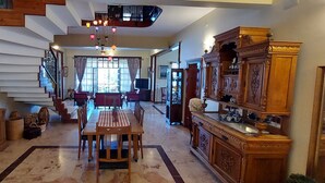 A spacious dining area with a wooden table and chairs, a staircase with white steps, and a large window with curtains. - Malikane Luxury Resort (Edremit)