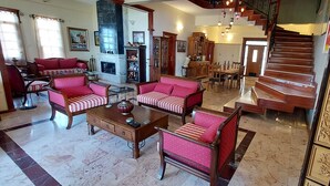 A spacious living room with a fireplace, a dining area, and a staircase leading to an upper floor. - Malikane Luxury Resort (Edremit)
