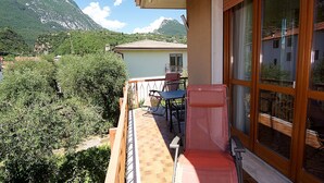 Un balcon avec une table et des chaises, donnant sur un paysage montagneux.