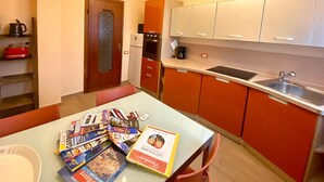 Une cuisine de taille réduite avec des meubles de couleur orange, un plan de travail blanc et un évier en acier inoxydable.