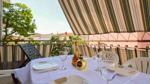 An outdoor dining area with a table set for two, featuring a bottle of wine, glasses, and plates. - Vacation home Ante by Interhome (Brodarica)