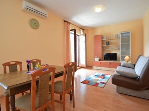 A dining area with a wooden table and chairs, a television on a cabinet, and a sofa in a living area. - Vacation home Ante by Interhome (Brodarica)