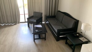 Een moderne hotelkamer met een bank, fauteuil en een klein tafeltje met een lamp.