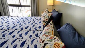 Een hotelkamer met twee bedden, elk voorzien van beddengoed met een patroon en een blauw kussen.