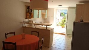 Une cuisine de taille réduite comprenant une table à manger, des chaises et un réfrigérateur.
