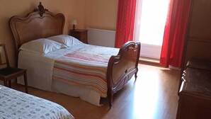Une chambre à coucher avec un grand lit, une table de chevet, une lampe et un radiateur.