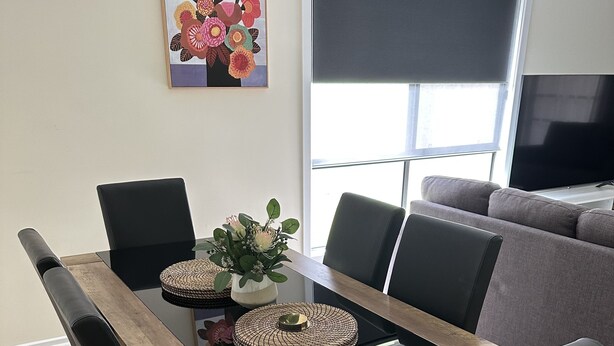 A dining table with black chairs, a wooden frame, and a centerpiece.