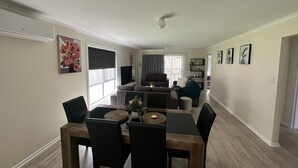 A modern living room with a sofa, a dining table with chairs, and a TV.