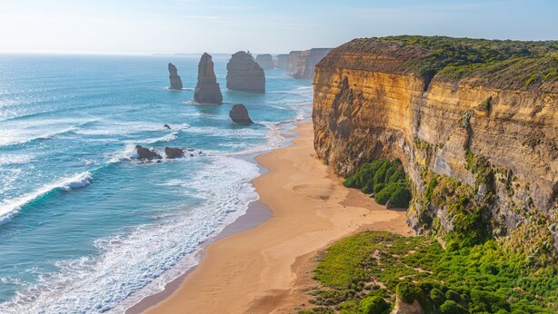 Un paysage côtier avec des falaises, une plage de sable et l’océan.